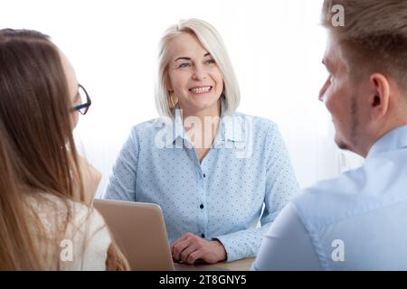Attractive aged businesswoman, mentor coach, speaking to young people, senior woman teaching the audience at a training seminar, female business Stock Photo