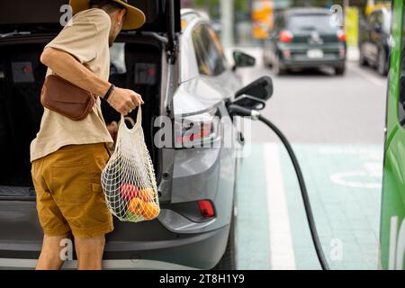 Man charging electric car while shopping Stock Photo
