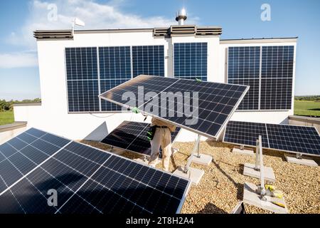 Man installing solar panels on a rooftop Stock Photo
