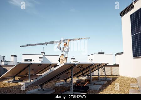 Man carries ladder during solar panels installation Stock Photo