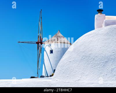 One of the windmills at Oia on the island of Santorini is an architectural feature among the white buildings. Stock Photo