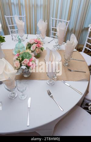 A round table is adorned with a vibrant display of fresh pink roses and white flowers, set up at a wedding reception Stock Photo