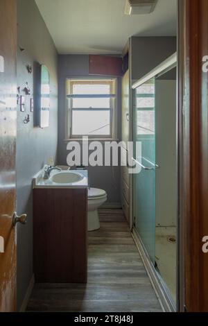 Narrow bathroom or loo in an old farmhouse for sale, needing a remodel. Kansas, USA. Stock Photo
