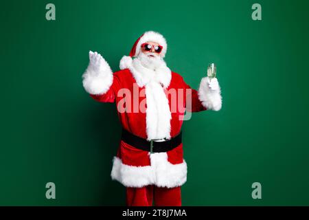 Photo of cheerful positive claus wear red costume drinking champagne telling christmas wishes isolated green color background Stock Photo