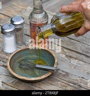 selfmade dressing for herb salad, vinegar, oil, salz and pepper are stirred in a bowl Stock Photo