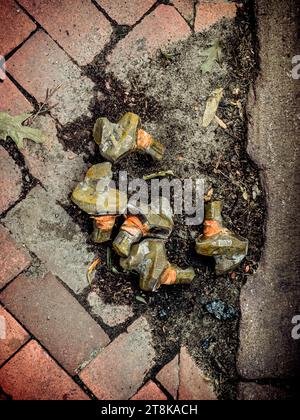Discarded rusted street hardware scattered along a worn brick sidewalk, creating an urban abstract of decay, neglect and forgotten infrastructure. Stock Photo