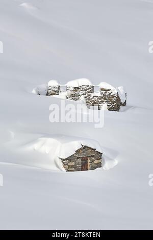 Ruined buildings in deep snow, high mountains Stock Photo