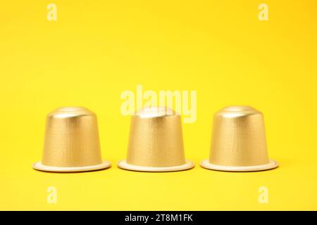 Three plastic coffee capsules on yellow background Stock Photo
