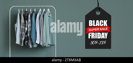 Rack with stylish clothes near color wall. Black Friday Sale Stock Photo