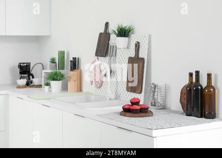 White kitchen counters with cutting boards, pegboard, sink and utensils Stock Photo