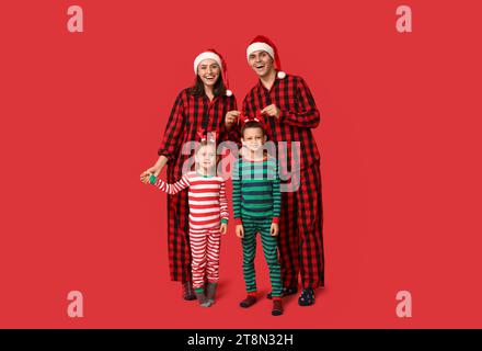 Happy family in Christmas pajamas on red background Stock Photo