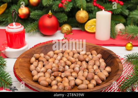 Hazelnuts in a wooden bowl on the background of the Christmas tree Stock Photo