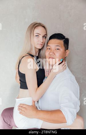 a woman sits on a man on a gray background Stock Photo