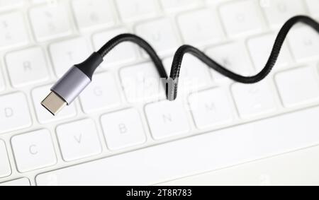 Usb type c cable against laptop keyboard background. Stock Photo