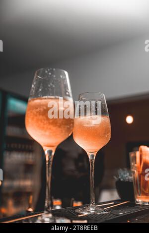 Glass of ice cold Aperol spritz cocktail served in a wine glass, placed on a bar counter Stock Photo