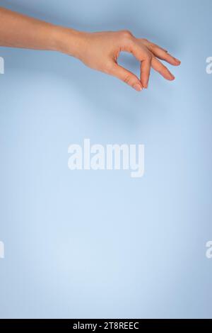 Hand gesture. Woman hand holding something on light blue background. Female hand holding some like blank card, business card, credit card Stock Photo
