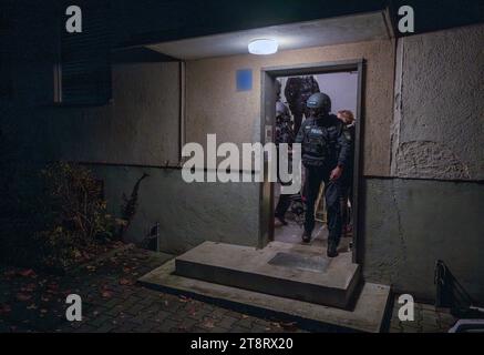 Munich, Germany. 21st Nov, 2023. Police officers leave a house during a search. Various properties throughout Bavaria were searched in the early hours of the morning during the 'Action Day PLUS against anti-Semitism'. Credit: Peter Kneffel/dpa - ATTENTION: House number has been pixelated for legal reasons/dpa/Alamy Live News Stock Photo