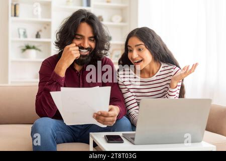 Smiling Millennial Indian Couple Discussing Total Amount Of Their Spends Stock Photo