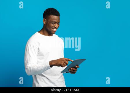 Happy young black guy using digital tablet Stock Photo
