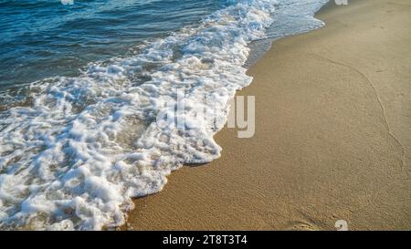 Sand beach and blue sea. Close up soft wave lapped the sandy beach. Beautiful sea waves with foam of blue and turquoise color isolated. Powerful ocean Stock Photo