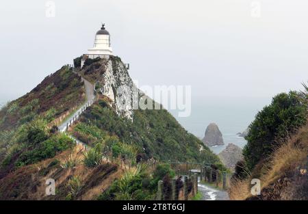 Nugget Point. Catlins NZ, Nugget Point is one of the most iconic landforms on the Otago coast. Located at the northern end of the Catlins coast, along the road from Kaka Point, this steep headland has a lighthouse at its tip, surrounded by rocky islets (The Nuggets Stock Photo