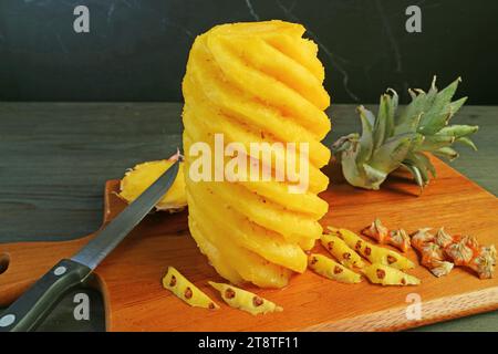 Peeled and cut fresh ripe pineapple on wooden cutting board Stock Photo