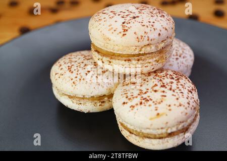Closeup of Mouthwatering Tiramisu Macarons on a Black Plate Stock Photo