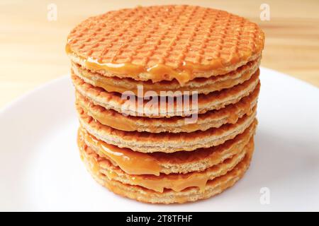 Stack of Mouthwatering Stroopwafels on the White Plate Served on Wooden Table Stock Photo