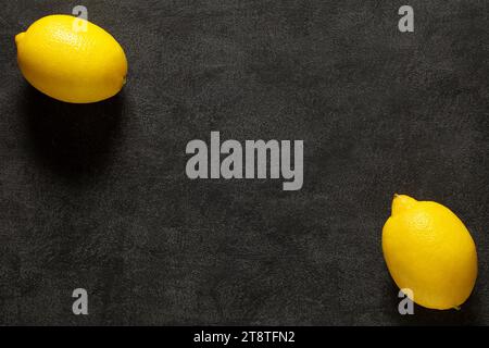 Lemons, two whole pieces on dark background, top view, space to copy text. Stock Photo