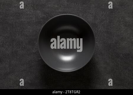 Bowl black empty deep, on dark background, top view, space to copy text. Stock Photo