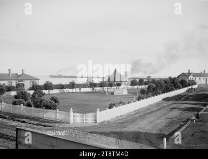 Victoria Reserve, Thames, View of Victoria Reserve enclosed by a white picket fence, looking towards the waterfront with the Shortland Wharf in the far distance. The band rotunda is in the middle distance. The building to the right is the Thames Railway Station. Photograph taken in early 1900s Stock Photo