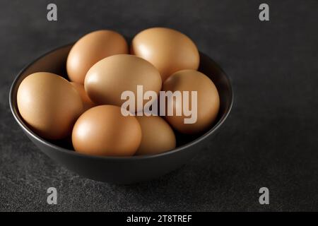 Eggs chicken, whole, in bowl on dark background, selective focus. Stock Photo