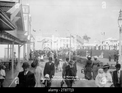 View of the entrance to Wonderland, Auckland, New Zealand Exhibition, Auckland, New Zealand Domain, View taken looking towards the entrance way (a man with his mouth wide open), with the pool and water chute on the righthand side. People are in the foreground walking to and from Wonderland. People can be seen on the righthand side looking at the activity in the pool area and up at the top of the water chute where the ride starts. P, 1 Jan 1914 at the Auckland, New Zealand Exhibition, Auckland, New Zealand Domain Stock Photo