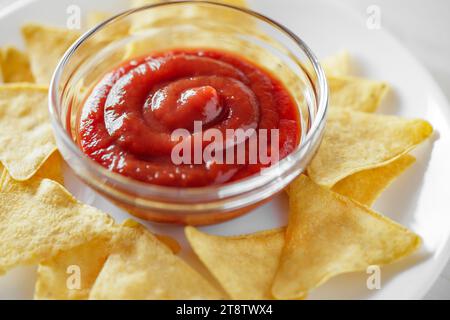 Nachos, with tomato salsa, on white plate, close-up, selective focus. Stock Photo