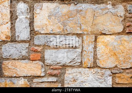 Wall from chipped stone, texture of brown and yellow stone background texture. Stock Photo