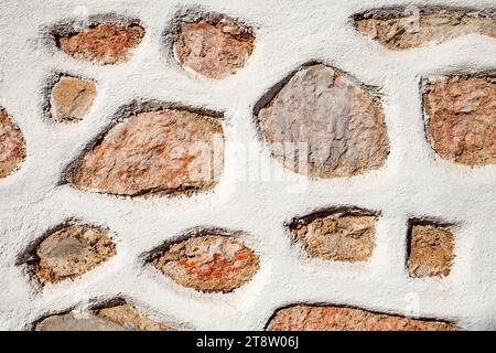 Wall from red and grey different stones background, texture irregular shapes, stone fence with white putty. Stock Photo