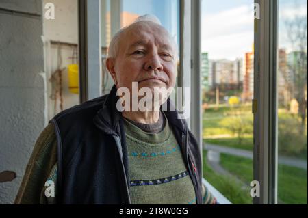 Portrait of a sad elderly man looking out the window at home. Lonely elderly man looking out the window Stock Photo