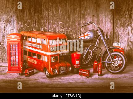 Still life photo on a playout of toy english mementos with tin bus, motobike and iconic phone booth on wooden shelf Stock Photo