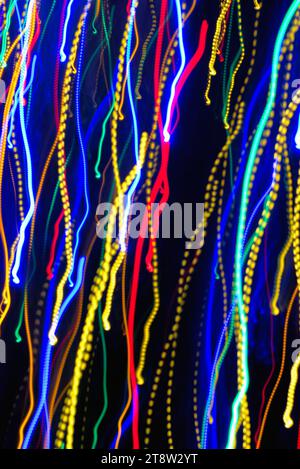 Blurred multi coloured light pattern streaks against a dark background creating abstract shapes Stock Photo