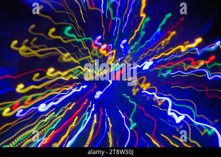 Blurred multi coloured light patterns streaks against a dark background creating abstract shapes Stock Photo