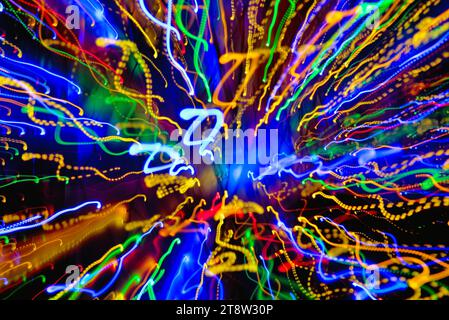 Blurred multi coloured light patterns streaks against a dark background creating abstract shapes Stock Photo