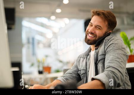 Male computer programmer talking on smart phone while working Stock Photo