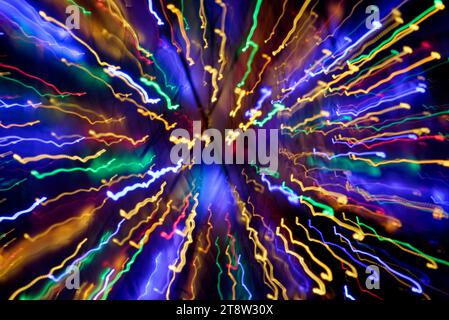 Blurred multi coloured light patterns streaks against a dark background creating abstract shapes Stock Photo
