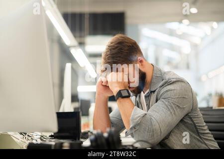 Stressed male entrepreneur sitting at desk while having a headache Stock Photo