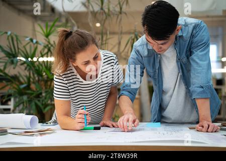Front view of architects leaning on table while working on blueprints Stock Photo