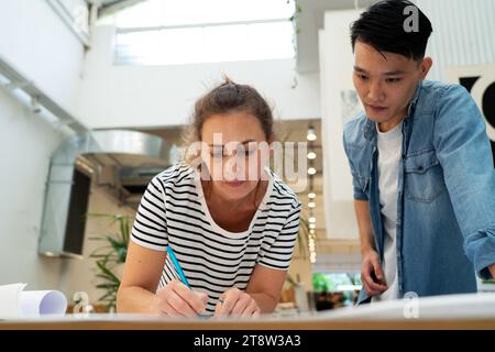 Female architect writing notes during meeting with colleague Stock Photo