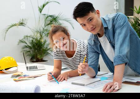 Two architects looking at the camera while leaning on table Stock Photo