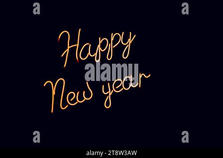 Glowing blurry orange inscription New Year on a black background. Vintage image in dark colors Stock Photo