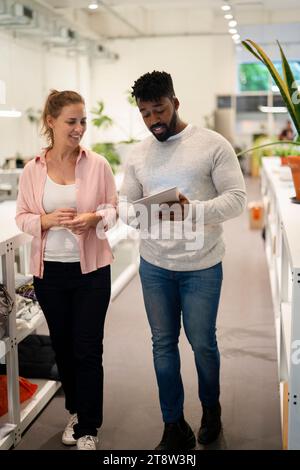 Two coworkers walking while discussing over digital tablet Stock Photo