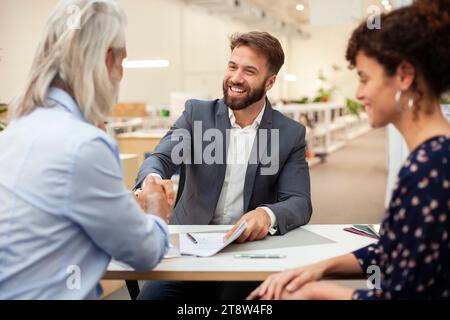 Real estate agent shaking hands with clients after signing contract Stock Photo